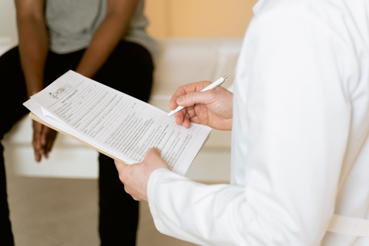 Healthcare professional reviews medical form during patient consultation in a clinic setting.